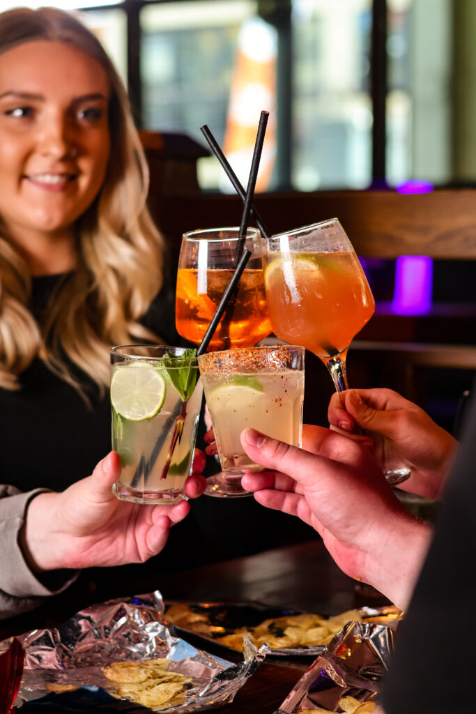 Group of friends toasting with cocktails at a modern Cardiff bar